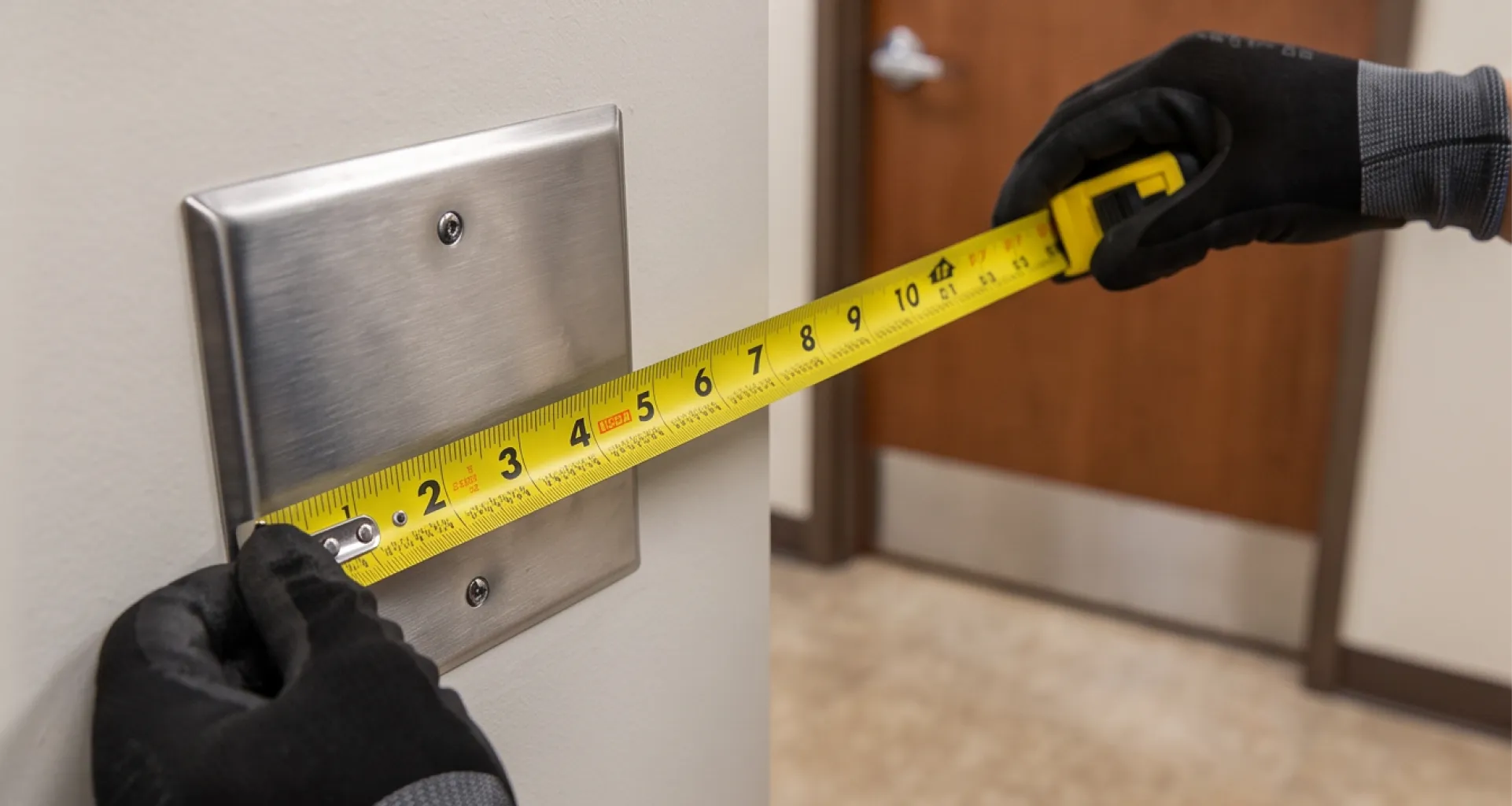 Tape measure checking the mounting height of an ADA push-plate actuator