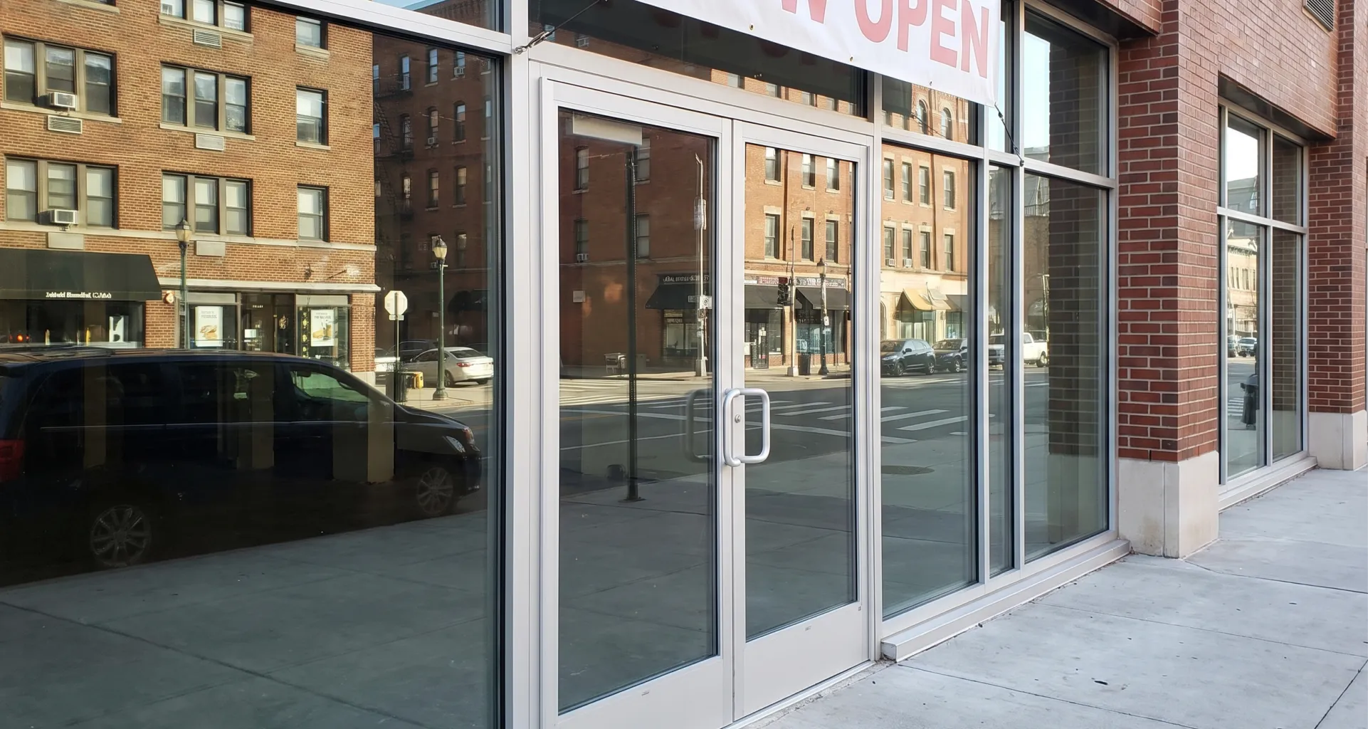 Replacement hollow metal door being rehung at a commercial entrance in daylight