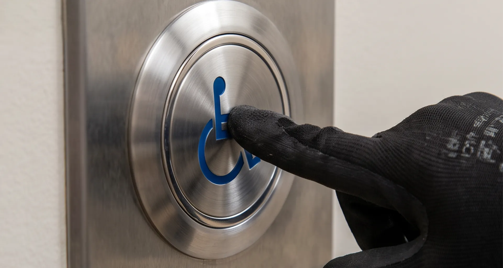 Stainless steel push plate with the wheelchair accessibility symbol being tested