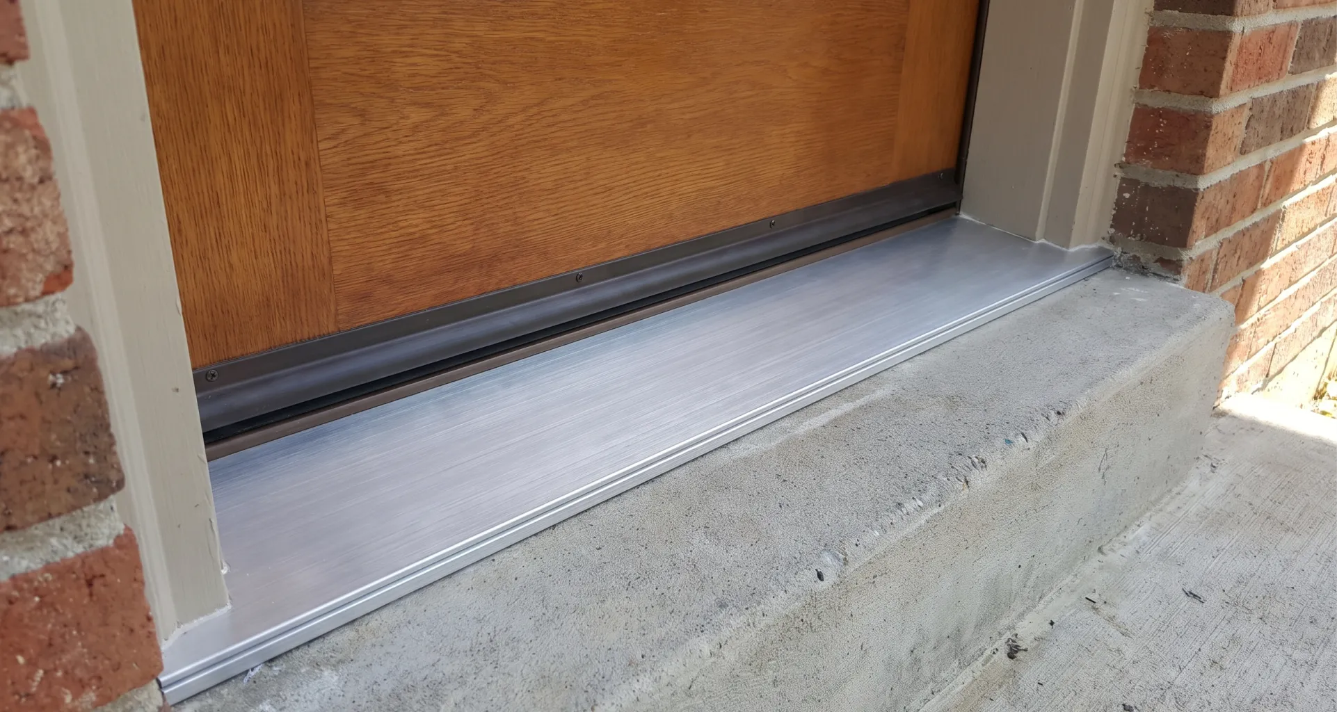 New aluminum threshold and door sweep sealing the base of an entry door